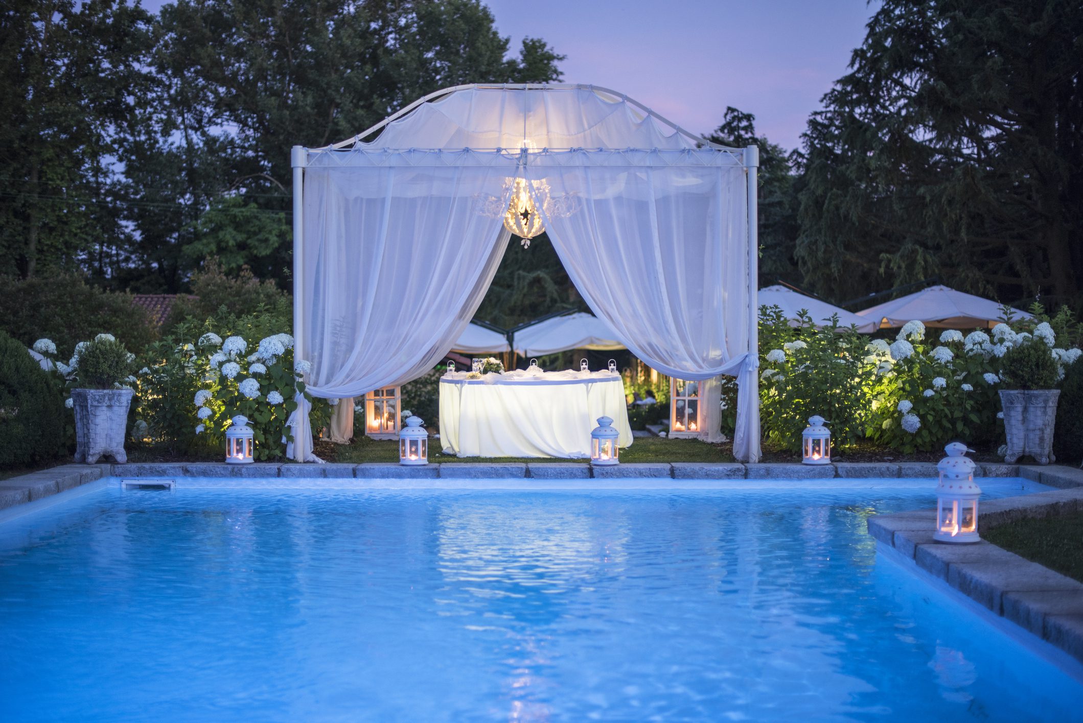 Illuminated wedding canopy beside a pool